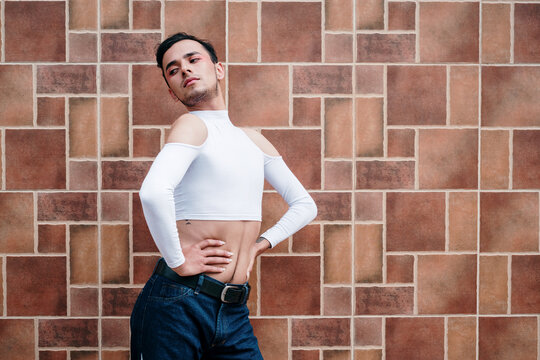 Sexy posture of a young homosexual man on a geometric wall