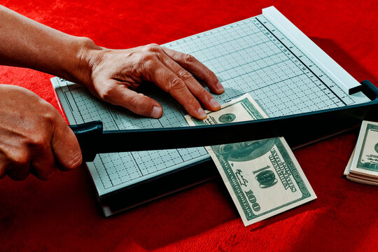 man is cutting a fake 100 dollar baknote