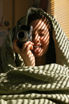 Teen resting on bed holding vintage camera