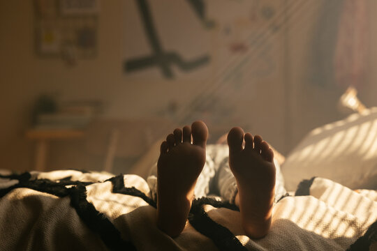 Unrecognizable teen resting on bed in own room