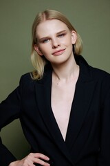 Attractive beautiful bright girl smiling looks into the camera posing in the studio in a suit on a green background