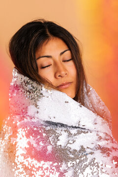 Female relaxing with sequin cape on colorful backdrop