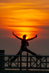 Fototapeta premium Silhouette of Thai woman jumping over sunset in the evening, Bangsan, Chonburi, Thailand.