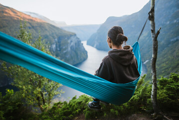 Man resting in hammock and watching Norwegian landscape