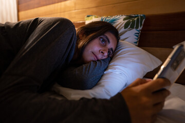 woman on bed using smartphone