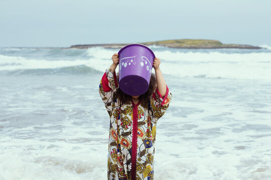 Young girl with curly hair at the beach pouring water on herself