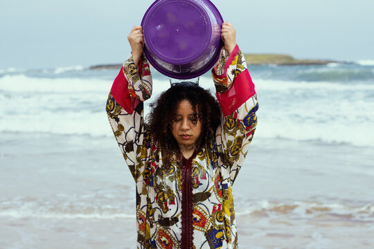Young girl with curly hair at the beach pouring water on herself