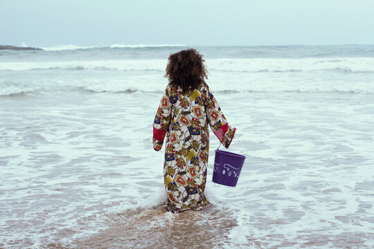 Young girl with curly hair walking water at the beach