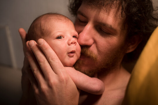 Loving father tenderly kissing newborn