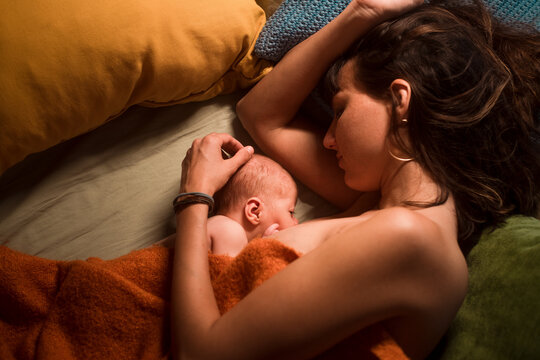 Baby breastfeeding on bed with mother