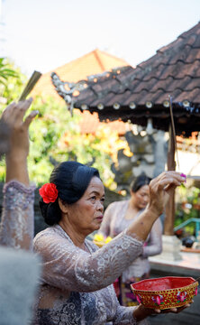 Balinese woman praying at Hindu altar with offerings 