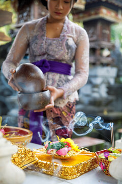 Young Balinese woman preparing offerings for Hindu ceremony
