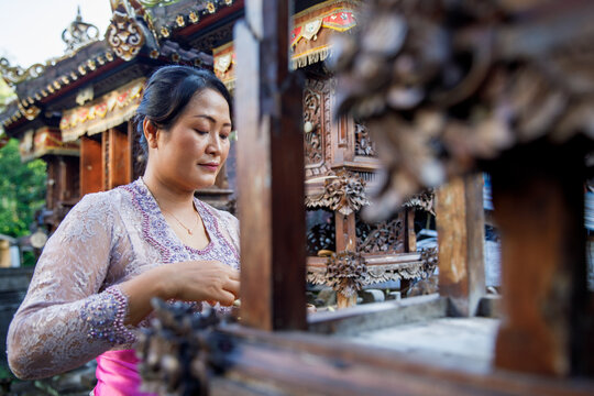 Balinese woman putting offerings on a family temple