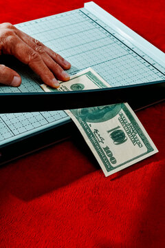man cuts a fake 100 dollar baknote