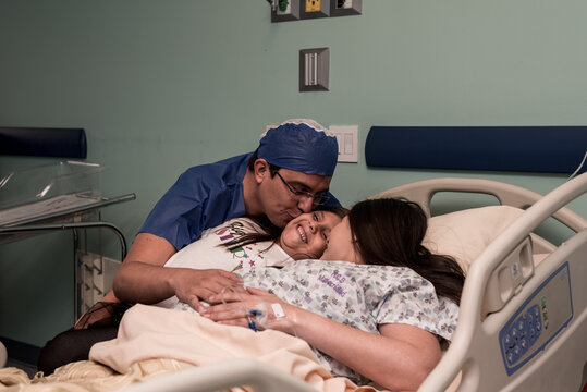 Parents kissing their daughter