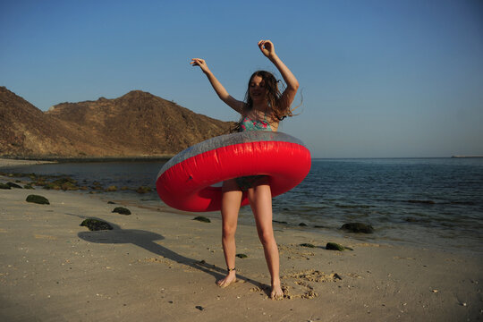 A girl plays with a raunbow coloured pool float at the beach