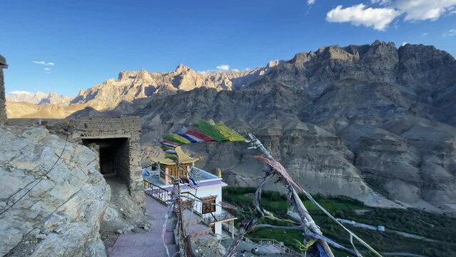 building of old traditional Tibetan Buddhist monastery with prayer flags in a stunning landscape view of a mountain valley in Himalayas