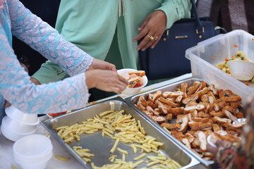 a woman in long clothes took fried chicken into a bowl