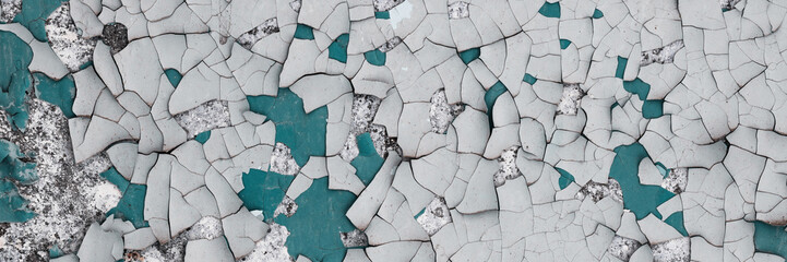 Peeling paint on the wall. Panorama of a concrete wall with old cracked flaking paint. Weathered rough painted surface with patterns of cracks and peeling. Wide panoramic texture for grunge background