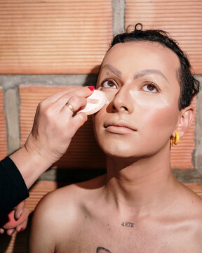 Makeup artist applying powder on a young man's face