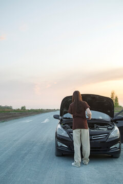 Unrecognizable Woman Fixing Car At Sunset