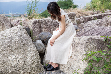 岩場に腰掛ける女性　Woman sitting on a rock