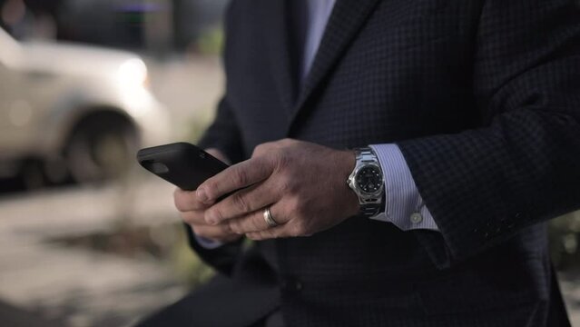 Close up of an texting on mobile phone outside with blurred background