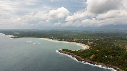 Fototapeta na wymiar Top view of coast with a beach and hotels among palm trees. Dickwella Beach, Sri Lanka.