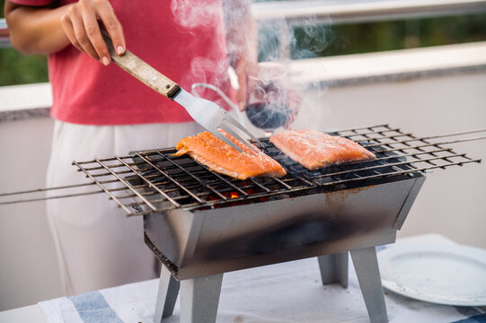 Crop woman grilling salmon on barbecue grid
