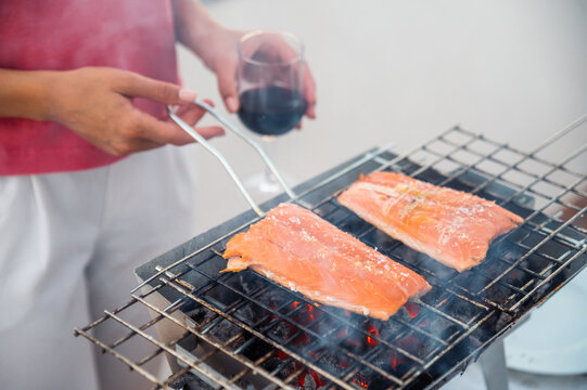 Crop woman grilling salmon on barbecue grid