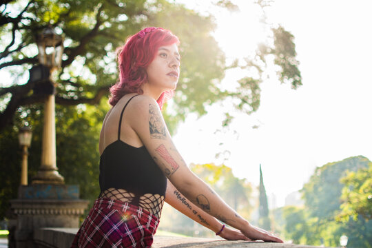 Alternative style non binary looking away in a park