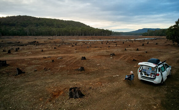 Man & camper in dry reservoir bed, drought, empty Lake King William