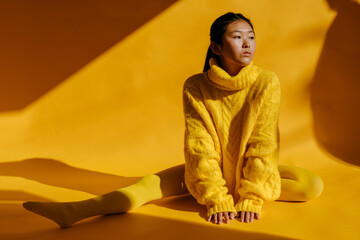Asian woman in sweater sitting in studio