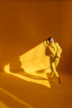 Asian woman dancing in yellow studio