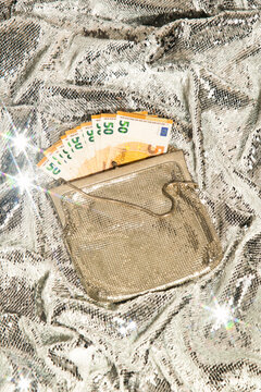 Euro cash money in a glitz purse against glittering background