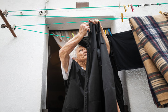 Elderly Woman Hanging Clothes Outdoors