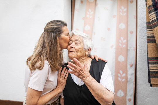 mature woman kissing elderly woman at the door of her house