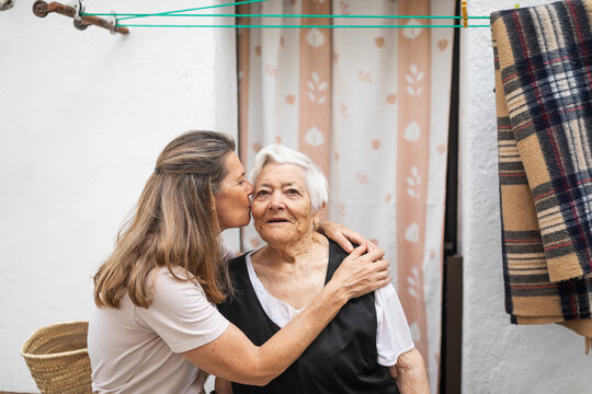 mature woman kissing elderly woman at the door of her house