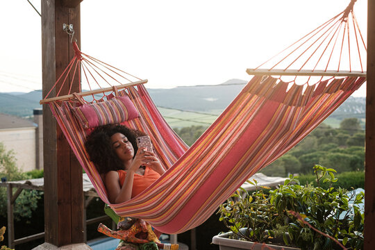 Woman using phone lying in a hammock