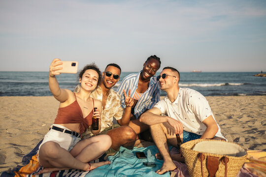 Multiracial group of friends taking selfies at the beach