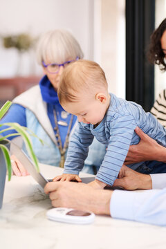 Baby using laptop with grandparents and mother
