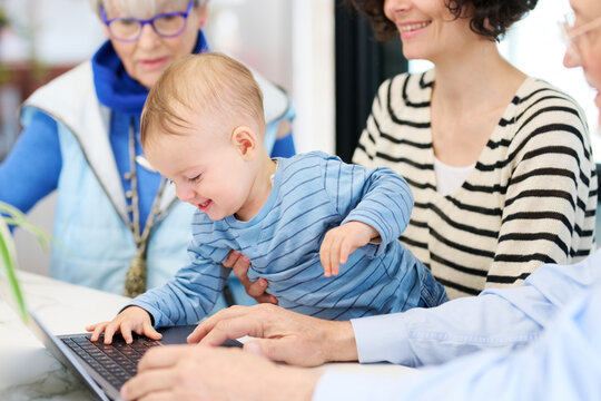 Baby using netbook near family