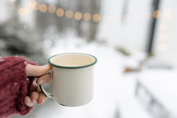 hand holding a coffee cup in snow 