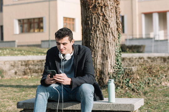 Boy Looking At Phone In A Park