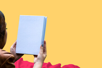 Mockup of a white blank hardcover book featuring a woman reading on summer themed orange background