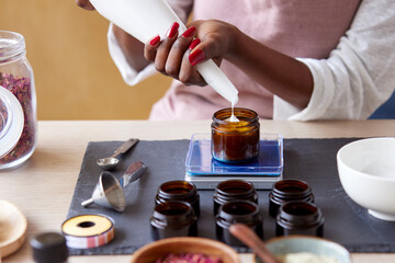 Cropped woman filling jar with cream on balance
