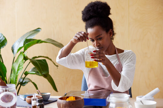 Black woman mixing cosmetic oil in beaker