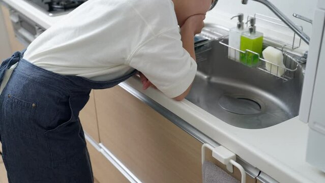 60p　妊娠してつわりに苦しむ料理中の女性（家事・主婦・キッチン）