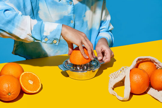 Crop female making orange juice