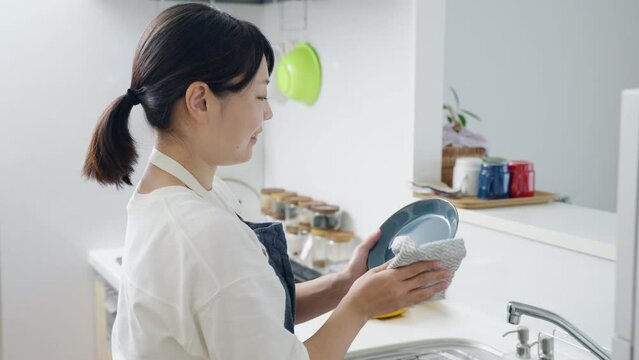 60p　キッチンで皿を拭く女性（家事・主婦）